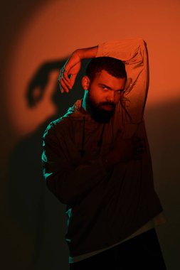 Yakışıklı bir adam, evin içinde güven içinde poz verirken göz alıcı bir şekilde parlak bir ışık sergiliyor..