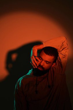 Genç bir adam rahat bir poz verir, rüya gibi bir yaz estetiğini oyuncu gölgelerle yakalar..