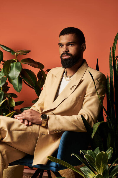 Стильный молодой человек уверенно позирует на теплом фоне ярких растений.