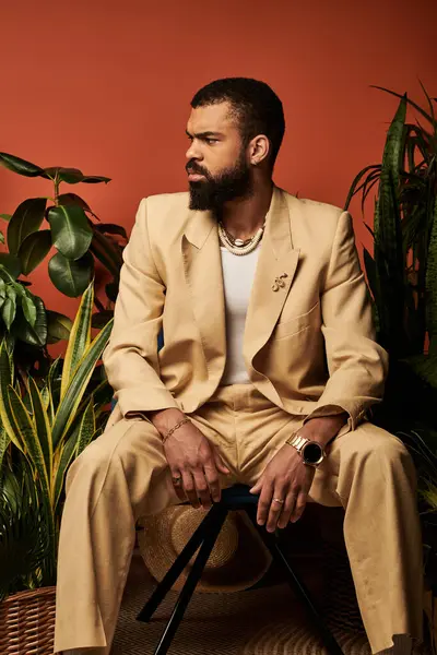 Şık bir yaz elbisesi içinde genç bir adam yemyeşil bitkilerin arasında güvenle oturur..