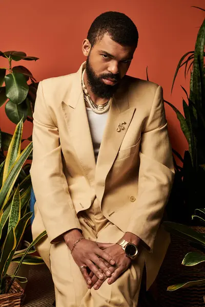 Şık bir adam, canlı bitkilerin arasında otururken yaz kıyafetlerine güvenir..