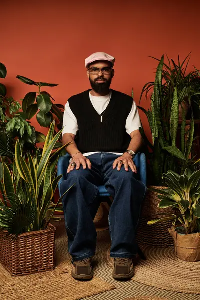 Yakışıklı bir adam yaz modasını sergiliyor. Kapalı alandaki yemyeşil evlerde dinlenirken..