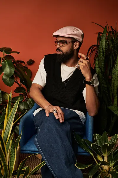 Yakışıklı bir adam, yaz modasına uygun giyinmiş, kendine güvenen, yemyeşil bir yerde oturuyor..