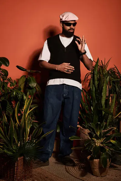 Şık bir genç adam canlı bitkilerin arasında duruyor, yaz moda anlayışını sergiliyor..