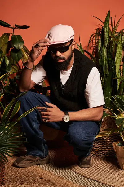 Genç bir adam, tropikal bitkiler arasında şık bir poz verir, yaz stilini ve cazibesini sergiler..