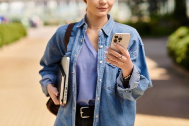 Parlak güneş ışığı, yoğun bir yolda akıllı telefonuyla meşgul olan kızıl saçlı kadını vurgular..