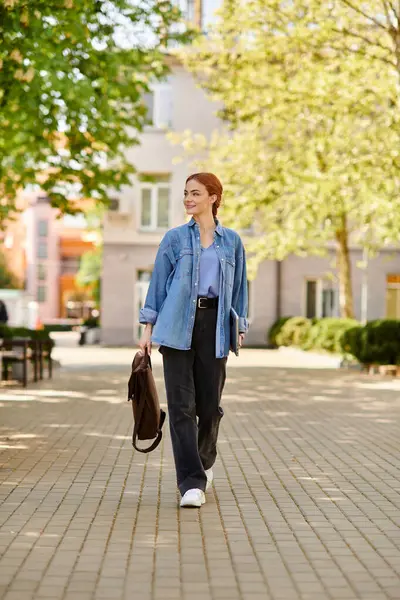 Kızıl saçlı bir kadın, güneşli bir günü yansıtan, canlı bir plazada güvenle yürüyor..