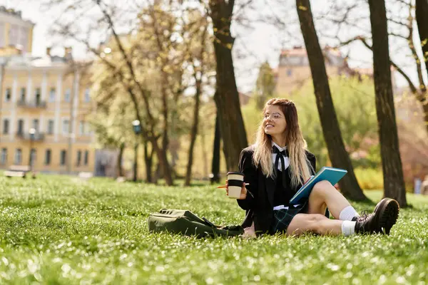 Güzel üniversite öğrencisi dışarıda kitap ve kahveyle dinleniyor, sıcak güneşte ıslanıyor..