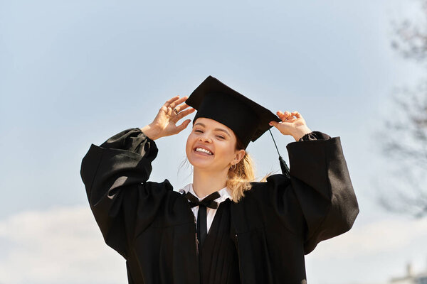 Девушка из колледжа в выпускном платье и кепке излучает счастье, празднуя успех.