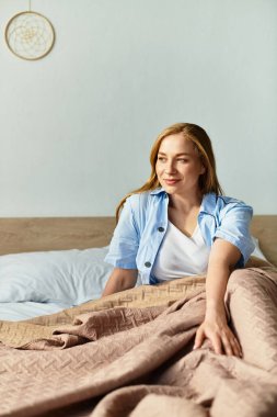 Genç bir kadın rahat bir şekilde yatağında oturur, evinde rahat bir sabah geçirir..