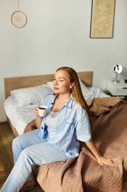 Genç bir kadın sıcak bir odada sıcak bir fincan kahvenin tadını çıkartıyor..