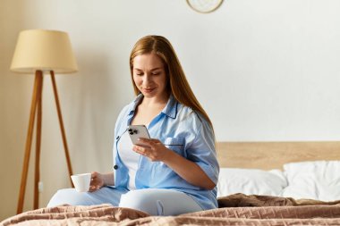 Genç bir kadın rahat bir yerde sabahtan zevk alır. Akıllı telefonunu kullanırken içkisini yudumlar..