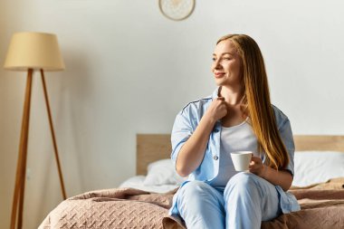 Elinde bir fincan çayla, genç bir kadın rahat yatak odasında huzurlu bir anın tadını çıkarıyor..