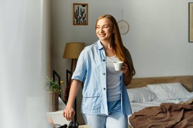 Genç bir kadın sıcak ve mutluluk saçan sıcak evinde bir fincan kahvenin tadını çıkarıyor..