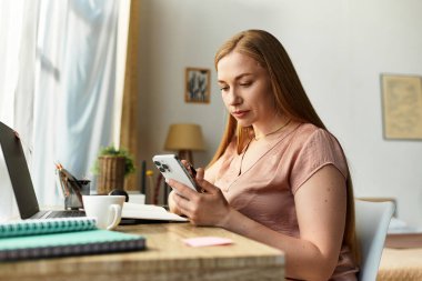 Genç bir kadın evinde rahat bir ortamda akıllı telefonuyla meşgul oluyor..