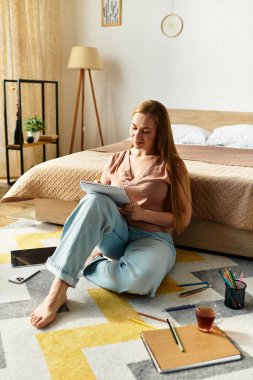 Genç bir kadın, evinde rahat bir şekilde otururken defterine çizim yapıyor..