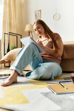 Genç bir kadın, sıcak ve davetkar bir yaşam alanında yerde çizim yapmaktan zevk alır..