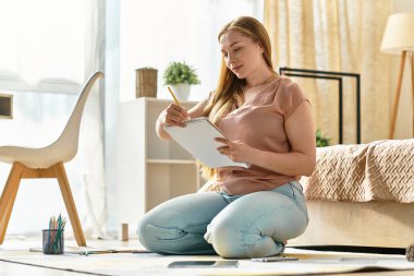 Genç bir kadın yerde oturuyor, defterine özenle çizim yapıyor..