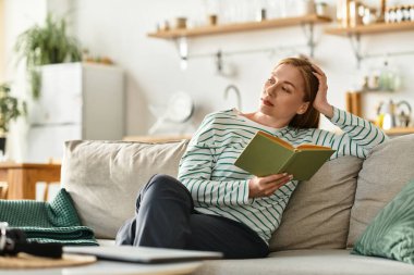 Genç bir kadın rahat evinde rahatça kitap okumaktan zevk alır..