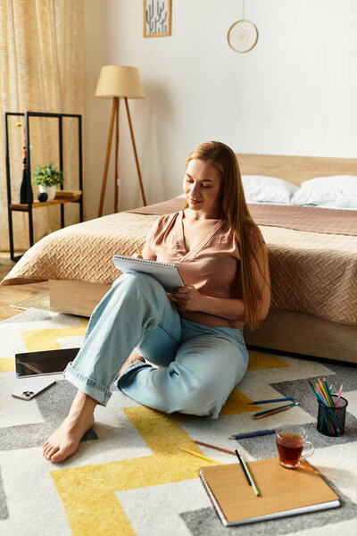 Молодая женщина расслабляется на полу, рисуя в блокноте, наслаждаясь своим уютным домом.