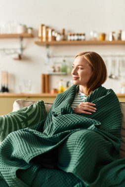 Genç bir kadın evinde uzanırken battaniyeye sarılı huzurlu bir anın tadını çıkarıyor..