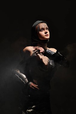 Genç bir kadın, esrarengiz bir şekilde sarmalanmış bir şato kıyafeti içinde zarafet saçar..