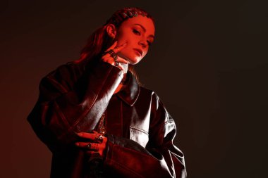 Genç bir kadın zarif ve çarpıcı aksesuarlarını düşük ışıkta sergiliyor..