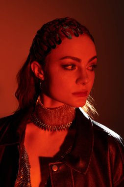 Modaya uygun giyinmiş büyüleyici genç bir kadın karamsar bir arka plana karşı zarafetini sergiliyor..