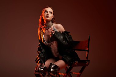 Zarif genç bir bayan zarif bir şekilde oturur, şık elbisesini ve duruşunu vurgular..