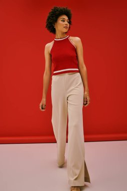 Genç bir kadın şık bir moda sergiliyor. Bir fotoğraf çekiminde kırmızı bir arka planda..