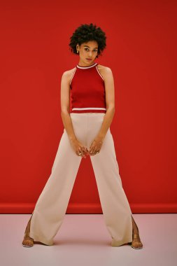 Kendine güvenen, modaya uygun giyinmiş genç bir kadın cesur bir arka plana karşı çıkıyor..