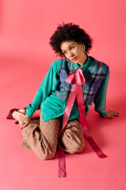 Şık, genç bir kadın, eşsiz bir elbisenin içinde canlı pembe bir arka plana karşı poz veriyor..