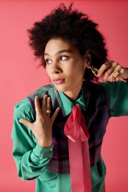 Kıvırcık saçlı çekici genç kadın şık kıyafetler ve çarpıcı aksesuarlarla zarifçe poz veriyor..