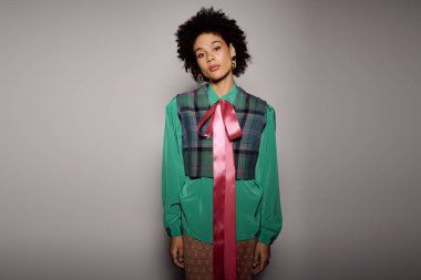 Kendine güvenen bir kadın stüdyoda poz veriyor, canlı modasını ve cesur tarzını sergiliyor..