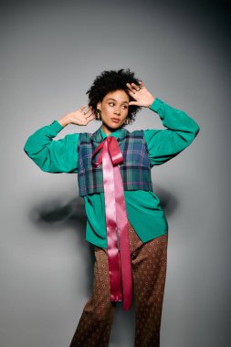 Genç bir kadın yaratıcı desenli ve desenli bir elbiseyle rahatça poz verir..