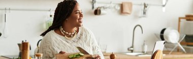 Genç bir Afrikalı Amerikalı kadın evinde hünerli bir salata pişiriyor, neşe saçıyor, bayrak dikiyor.