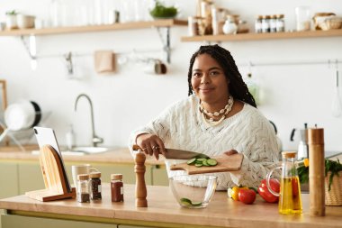 Genç siyah bir kadın mutfağında lezzetli bir salata yapmaktan hoşlanıyor..