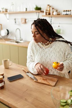 Genç bir Afrikalı Amerikalı kadın, sıcak ve davetkar mutfağında ustalıkla taze bir salata hazırlıyor..