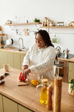 Genç bir Afrikalı Amerikalı kadın evde lezzetli bir salata yapmak için ustalıkla sebze doğruyor..