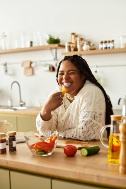Genç bir Afrikalı Amerikalı kadın canlı bir salata hazırlarken yemek yapmaktan ve gülümsemekten hoşlanır..