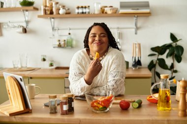 Genç bir Afrikalı Amerikalı kadın evde canlı bir salata yapmaktan zevk alıyor, yemek pişirmenin hazzını kucaklıyor..