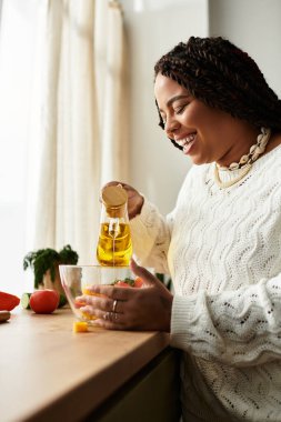 Genç Afrikalı Amerikalı kadın evde taze malzemelerle canlı bir salata hazırlıyor..