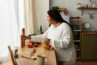 Genç bir Afrikalı Amerikalı kadın sıcak mutfağında dururken canlı bir salata yapmaktan hoşlanıyor..