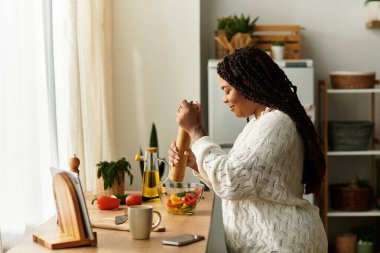 Genç bir Afrikalı Amerikalı kadın evde canlı bir salata için ustaca sebze doğruyor..
