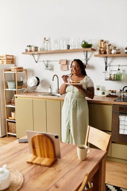 Genç bir Afrikalı Amerikalı kadın mutfağında dururken besleyici bir salata yiyor..