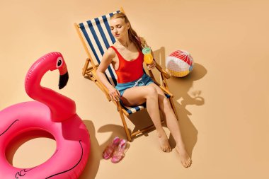 Genç bir kadın havuzun kenarındaki sandalyede dinleniyor, güneşin tadını çıkarıyor..