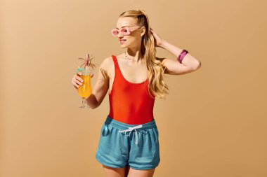 Şık, genç bir kadın kendinden emin bir şekilde canlı bir içki tutuyor, yaz havasını kucaklıyor..