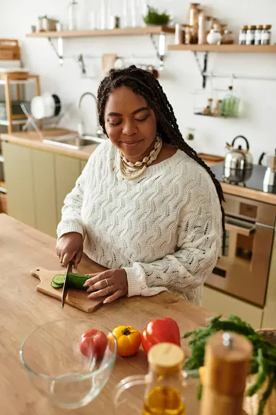Genç siyah bir kadın, sıcak mutfağında renkli bir salata yapıyor..