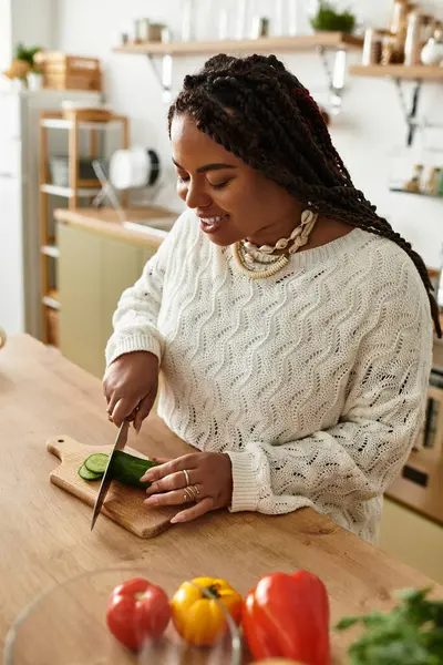 Genç Afro-Amerikan bir kadın evde sebzeleri ustalıkla doğruyor ve canlı bir salata yapıyor..