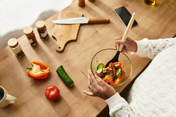 Young woman prepares a colorful salad at home, enjoying healthy cooking with fresh ingredients.